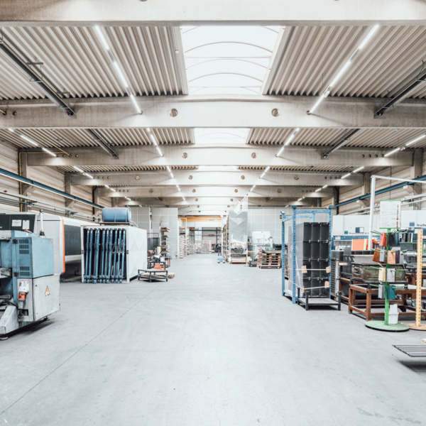 Bild einer Produktionshalle, in der einige Maschinen und Materialien stehen.