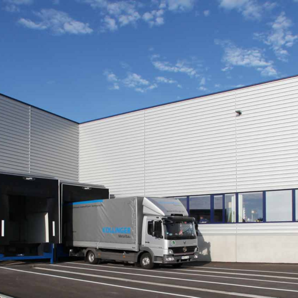 Bild einer Logistikhalle vor der ein LKW steht.