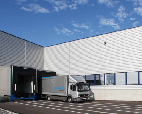 Bild einer Logistikhalle vor der ein LKW steht.