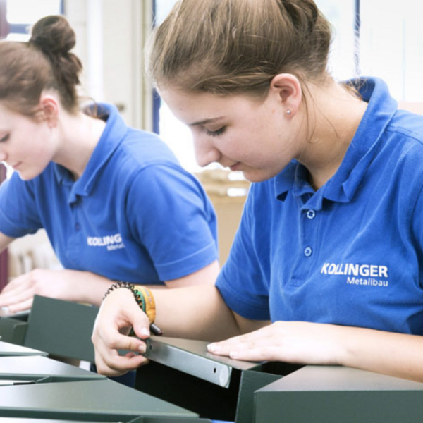 Zwei Mädchen arbeiten in einer Produktionshalle und trage blaue T-Shirts mit der Aufschrift "CB Kollinger".